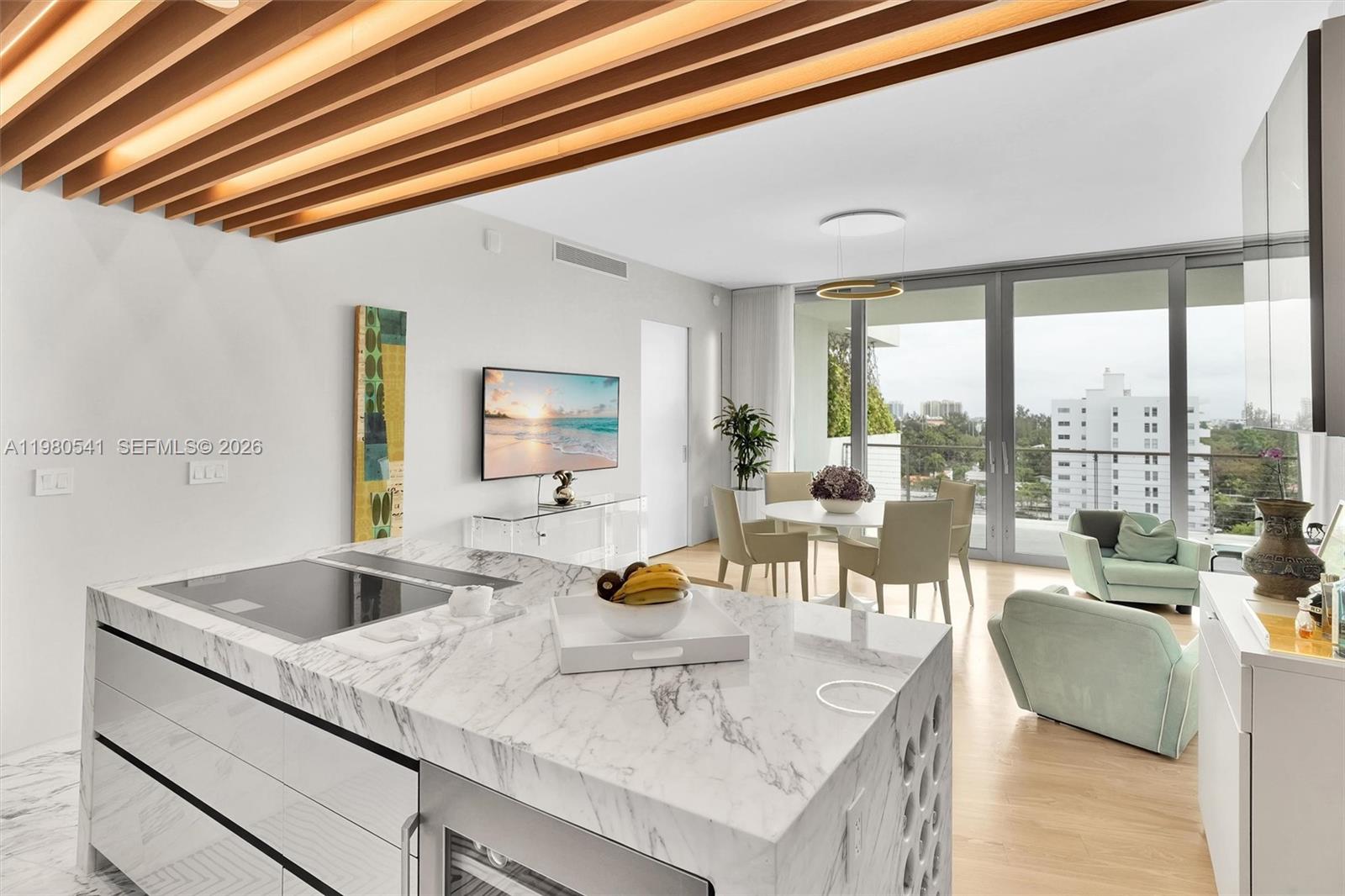 A modern kitchen with a marble island overlooks a dining area and a living room — 1300 Monad Ter # 7C, Miami Beach FL 33139, MIAMI BEACH, FL