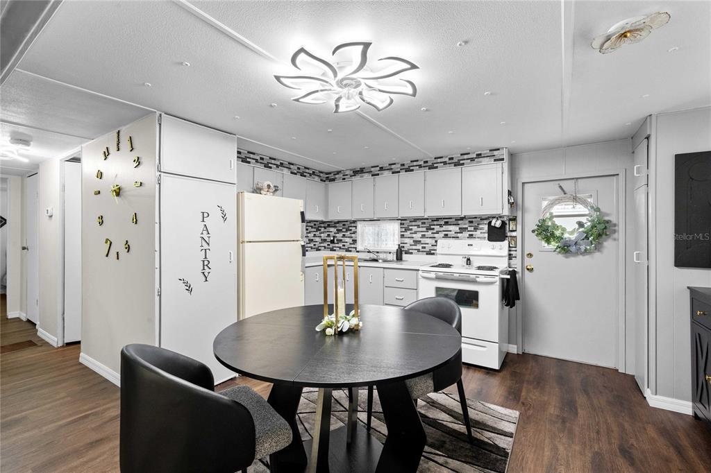 A kitchen features a round dining table, white cabinetry, a pantry door, and a light fixture — 37135 SANDRA AVENUE, ZEPHYRHILLS, FL