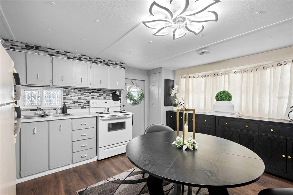 A kitchen and dining area with gray cabinets, a white stove, and a black table — 37135 SANDRA AVENUE, ZEPHYRHILLS, FL