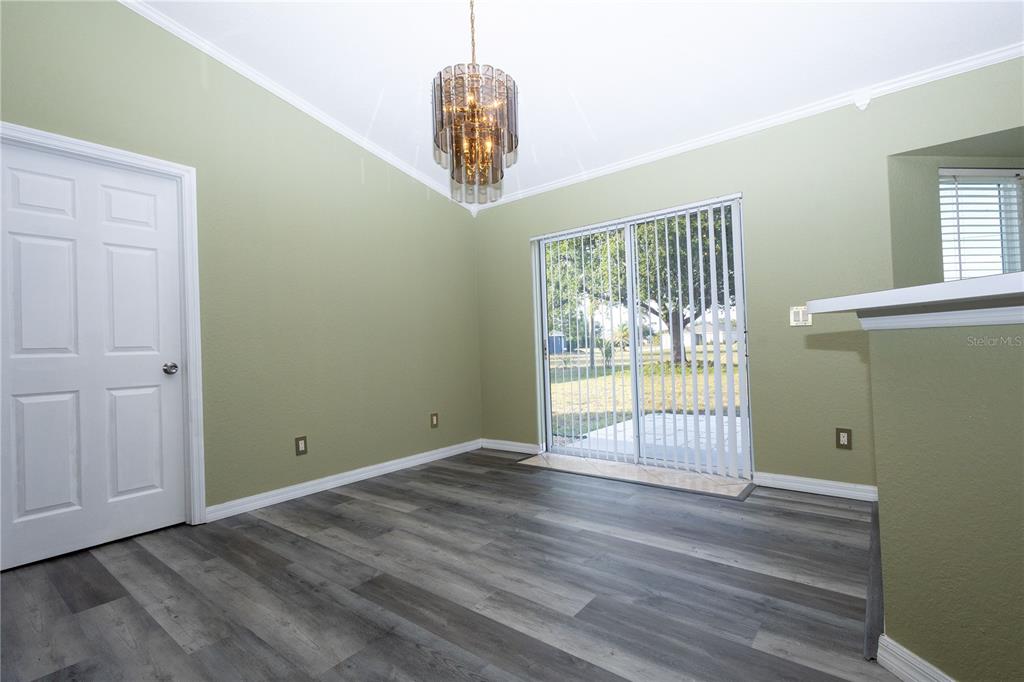A dining room with sage green walls, gray wood-look flooring, and a glass sliding door — 25324 LYCHEE COURT, PUNTA GORDA, FL