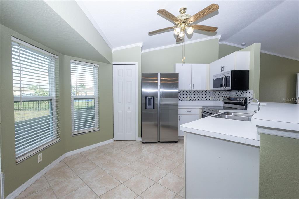 A kitchen with stainless steel appliances, white cabinets, a ceiling fan, and tiled flooring — 25324 LYCHEE COURT, PUNTA GORDA, FL