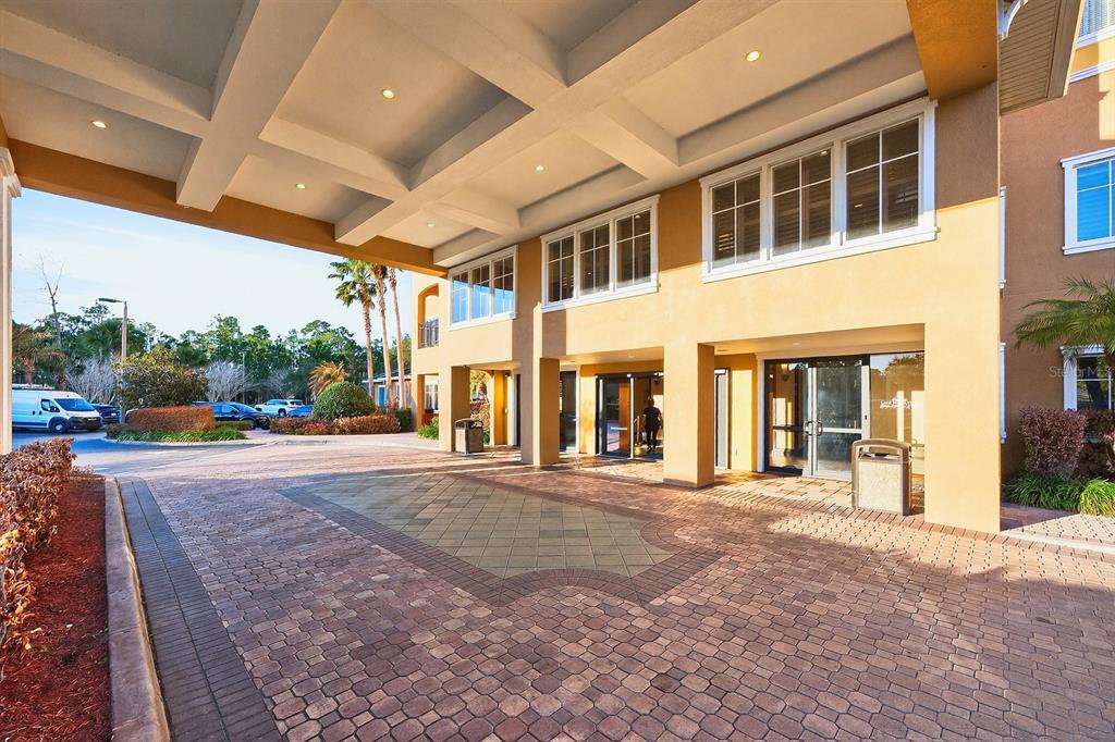 A paved driveway leads to the covered entrance of a multi-story tan building — 8125 RESORT VILLAGE DRIVE UNIT 5901, ORLANDO, FL
