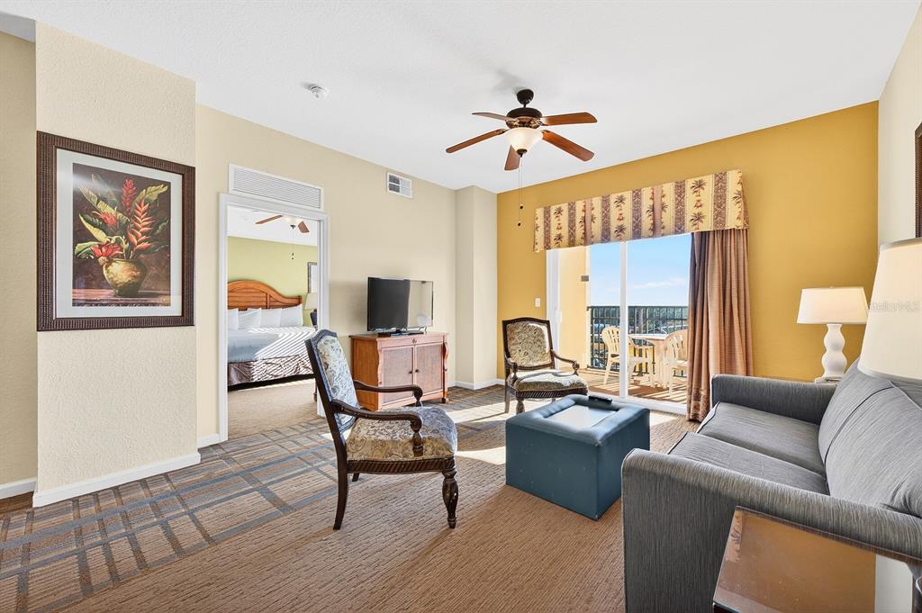 A living room with a sofa, armchairs, a television, and a balcony view — 8125 RESORT VILLAGE DRIVE UNIT 5901, ORLANDO, FL
