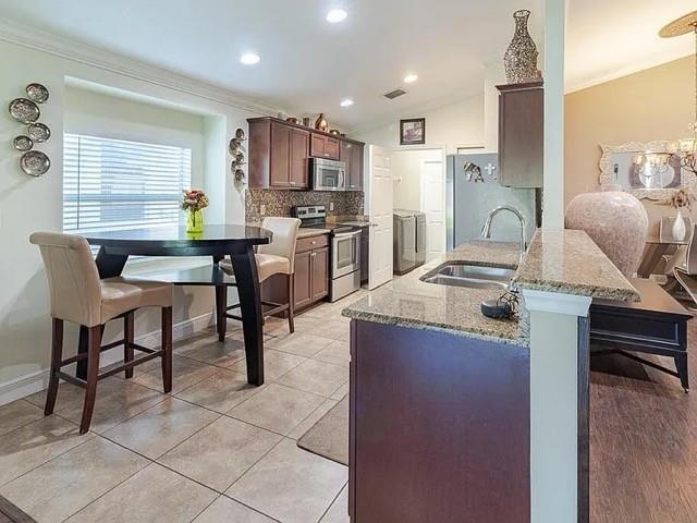 A kitchen features dark wood cabinets, granite countertops, a breakfast table, and tile flooring — 9446 Windrift Circle, Fort Pierce FL 34945, FORT PIERCE, FL
