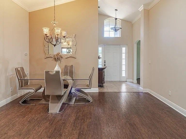 A dining area with a glass table, modern chairs, and a chandelier, opening to an entryway — 9446 Windrift Circle, Fort Pierce FL 34945, FORT PIERCE, FL