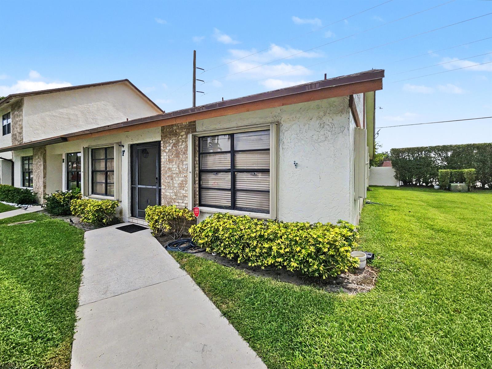 A single-story residential building with a concrete walkway, stucco walls, and a brick facade — 1160 Parkside Green Drive # F, FL 33415, FL