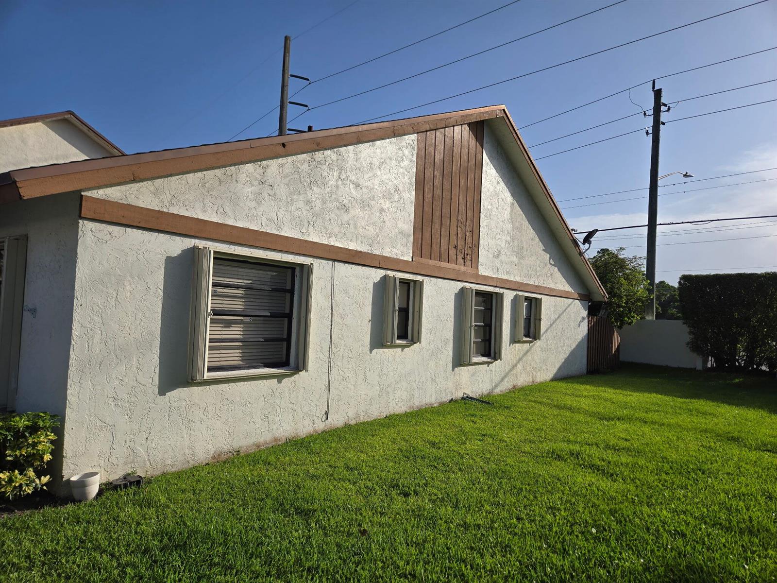 The exterior side of a white stucco house features brown trim and several windows — 1160 Parkside Green Drive # F, FL 33415, FL