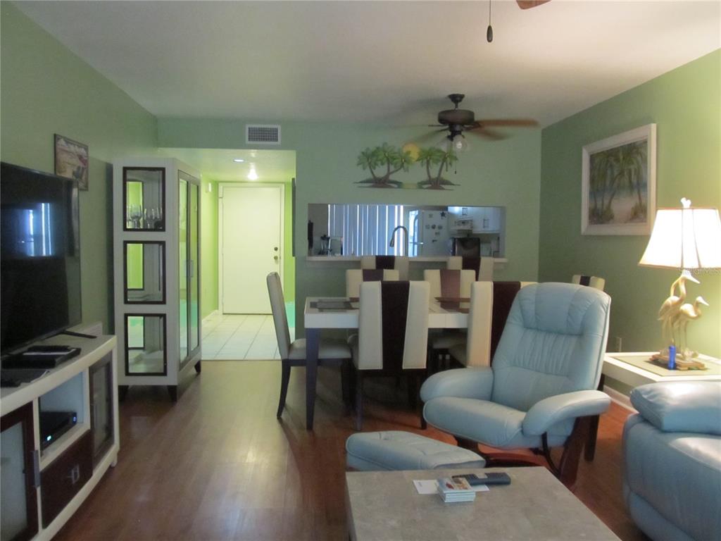 A living room and dining area with green walls, wood flooring, and a light blue recliner — 4733 WINSLOW BEACON UNIT 13, SARASOTA, FL
