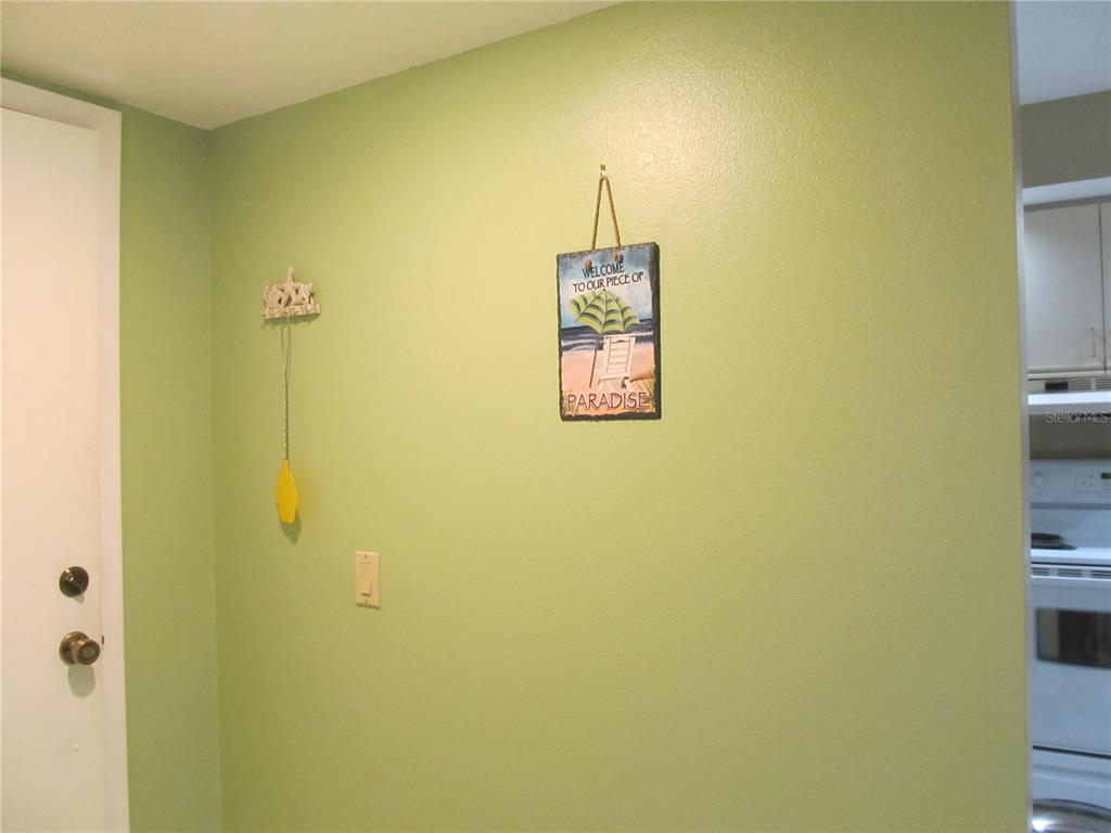 A light green wall features a hanging beach-themed sign and a small decorative ornament — 4733 WINSLOW BEACON UNIT 13, SARASOTA, FL