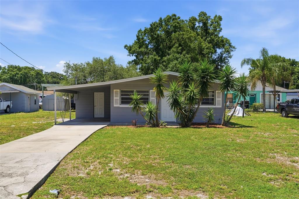 A single-story gray house with a carport and palm trees in the front yard — 3214 AVENUE Q NW, WINTER HAVEN, FL