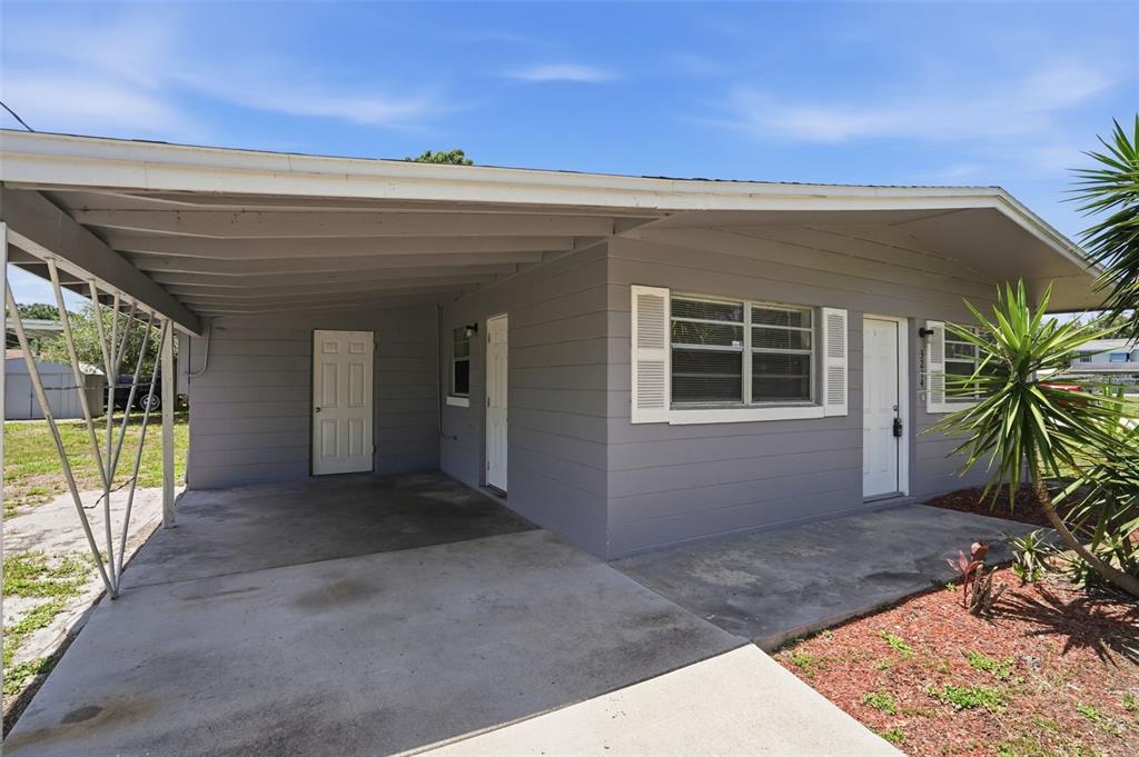 A gray single-story house features a concrete carport and a front entrance with shutters — 3214 AVENUE Q NW, WINTER HAVEN, FL