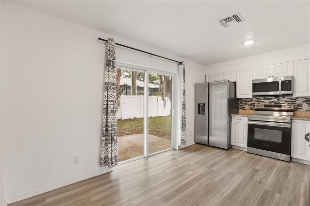 A kitchen with white cabinets, stainless steel appliances, and a sliding glass door to a yard — 4650 BOCA VISTA COURT, ORLANDO, FL