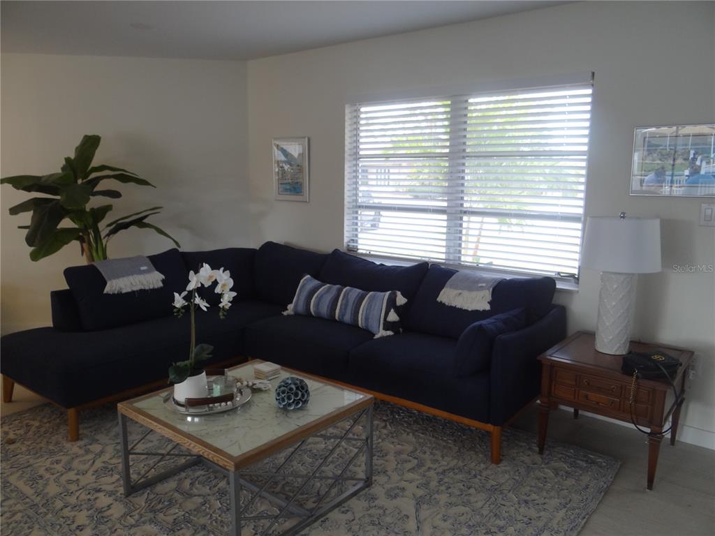 A living room features a dark blue sectional sofa, a glass-topped coffee table, and a window — 2473 ROSA LANE, PUNTA GORDA, FL