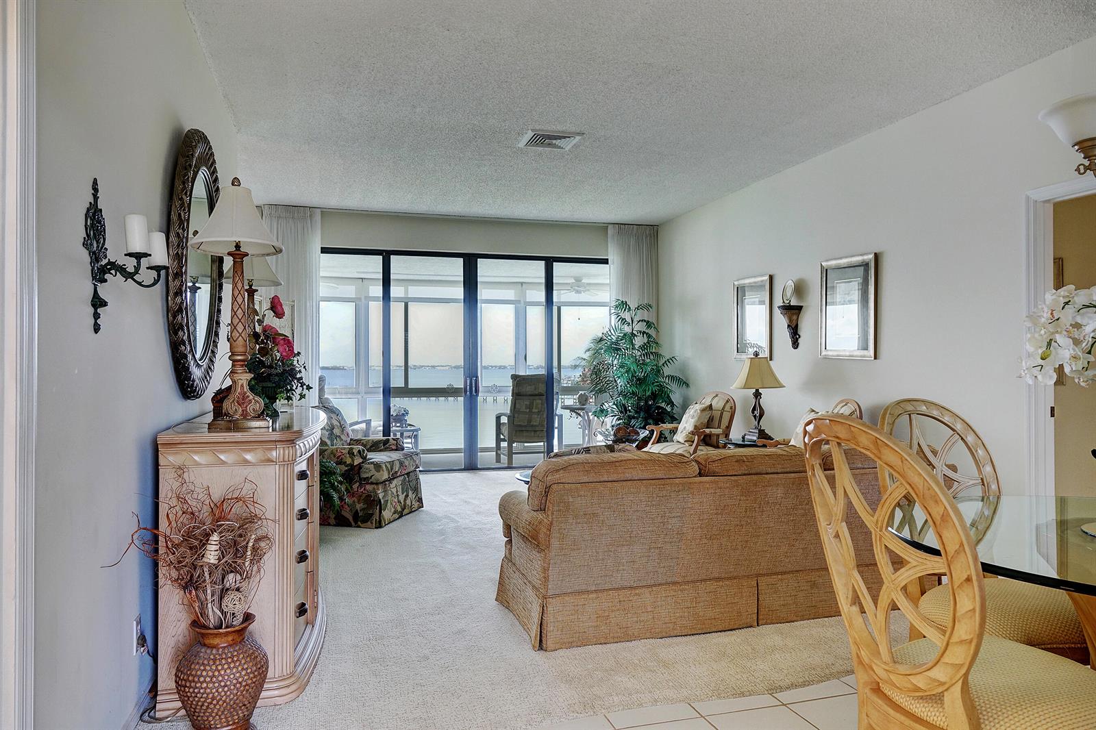 A living room with beige carpet, a sofa, a dresser, and a sliding glass door balcony — 2370 NE Ocean Boulevard # C305, Stuart FL 34996, STUART, FL