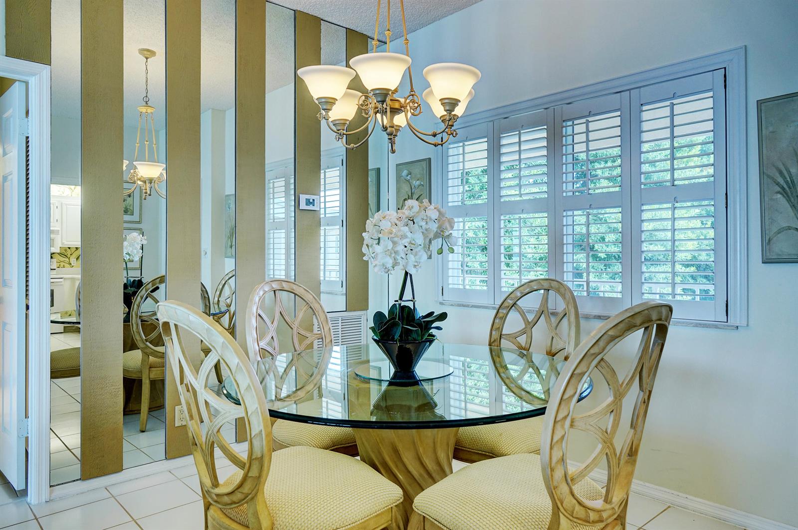 A dining room features a glass-topped table, four chairs, a chandelier, and mirrored wall panels — 2370 NE Ocean Boulevard # C305, Stuart FL 34996, STUART, FL
