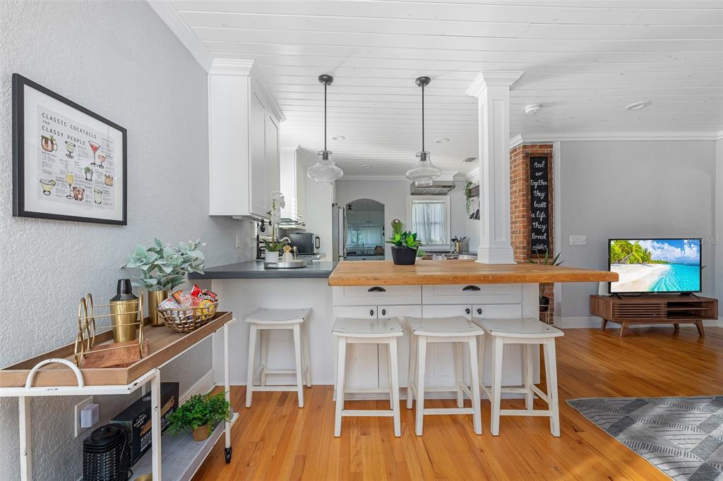 A kitchen features a wooden breakfast bar, white cabinetry, pendant lighting, and hardwood flooring — 2007 CORNELL AVENUE, WINTER PARK, FL