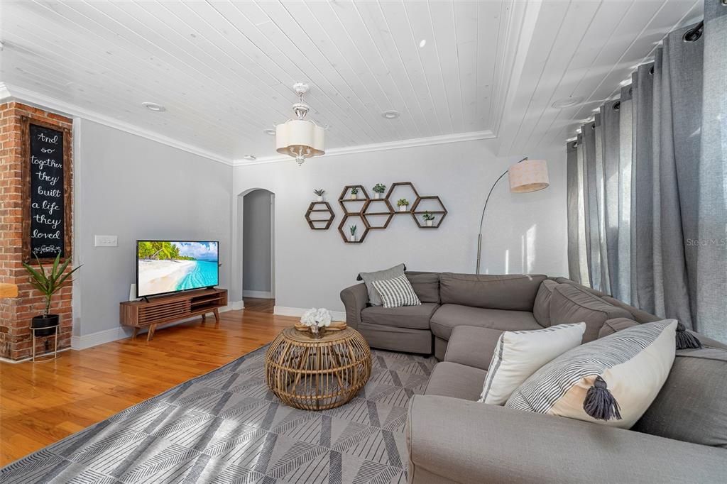 A living room features a gray sectional sofa, wood floors, a brick accent wall, and shelving — 2007 CORNELL AVENUE, WINTER PARK, FL