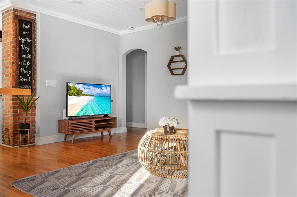 A living room features hardwood floors, a brick accent wall, and a television on a stand — 2007 CORNELL AVENUE, WINTER PARK, FL