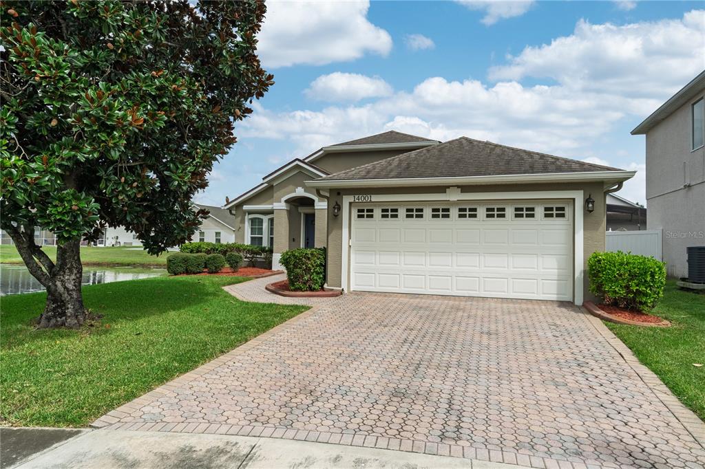 A single-story house with a paved driveway, a two-car garage, and a large tree — 14001 FAIRWINDS COURT, ORLANDO, FL