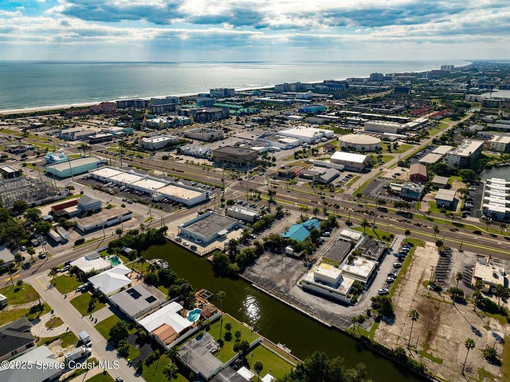 An aerial view shows a coastal town with buildings, a canal, and the ocean — 333 W COCOA BEACH CAUSEWAY UNIT 5, COCOA BEACH, FL