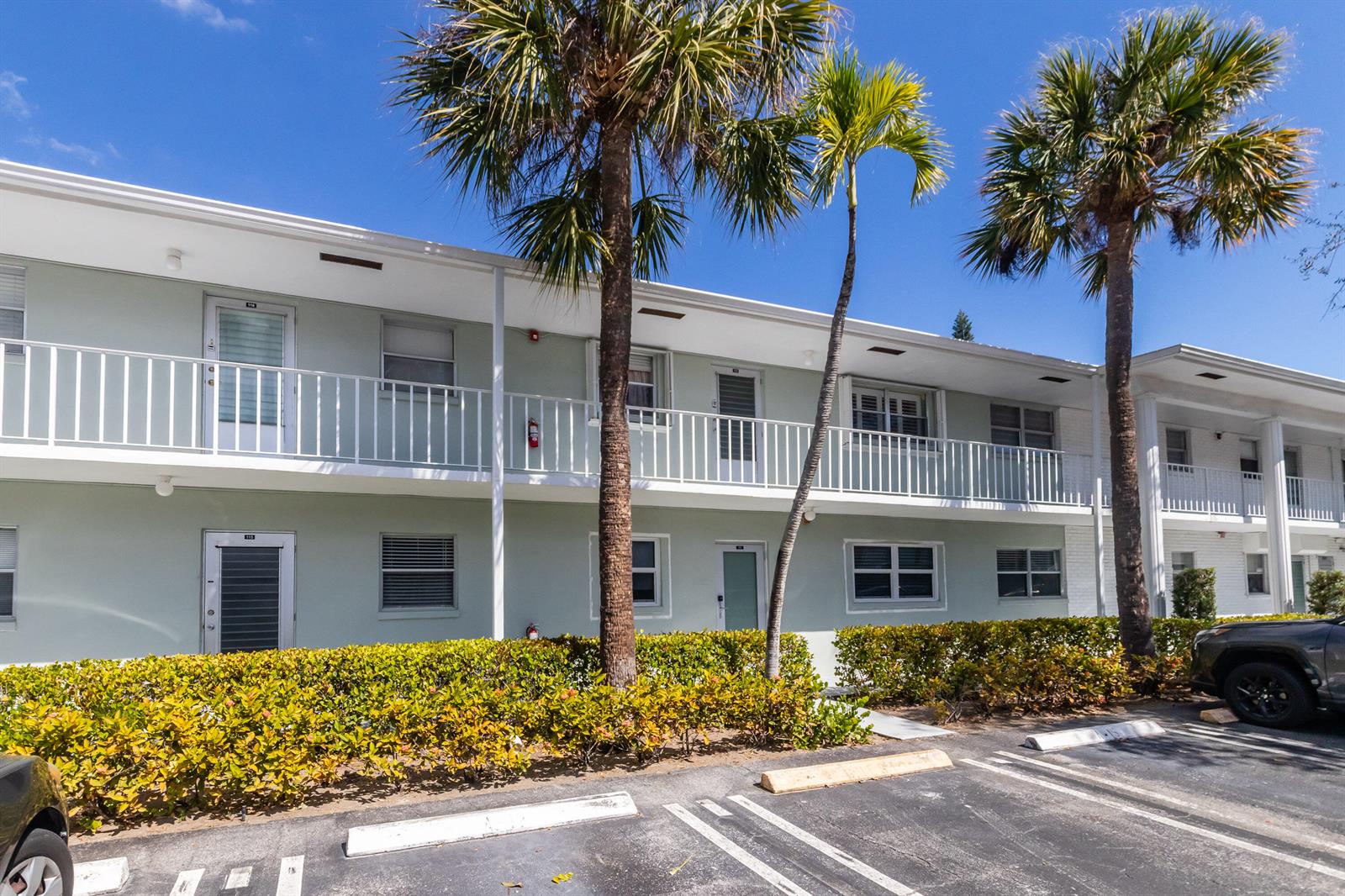 A two-story apartment building with a white balcony, palm trees, and a parking lot — 2300 NW 22nd Avenue # 112, Delray Beach FL 33445, DELRAY BEACH, FL