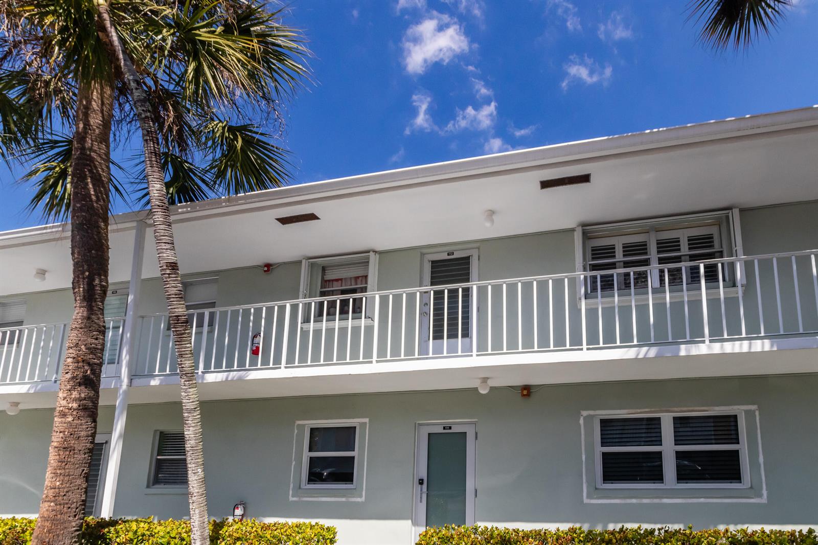 A two-story apartment building exterior features a balcony, palm trees, and light green siding — 2300 NW 22nd Avenue # 112, Delray Beach FL 33445, DELRAY BEACH, FL