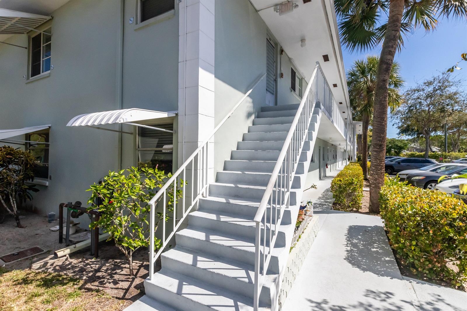 An exterior view of a two-story apartment building featuring a concrete staircase and metal railings — 2300 NW 22nd Avenue # 112, Delray Beach FL 33445, DELRAY BEACH, FL