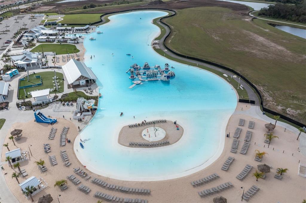 An aerial view shows a large turquoise lagoon with an inflatable obstacle course and beach — 17066 OVAL RUM DRIVE, WIMAUMA, FL