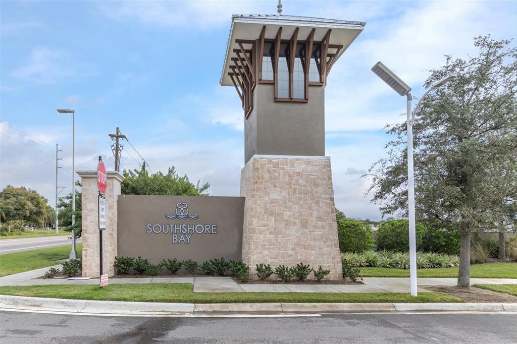 A stone monument sign for Southshore Bay stands near a road under a cloudy sky — 17066 OVAL RUM DRIVE, WIMAUMA, FL