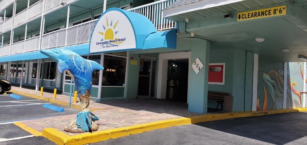 The exterior of the Clearwater Beach Hotel features a blue awning and a dolphin statue — 504 S GULFVIEW BOULEVARD, CLEARWATER, FL
