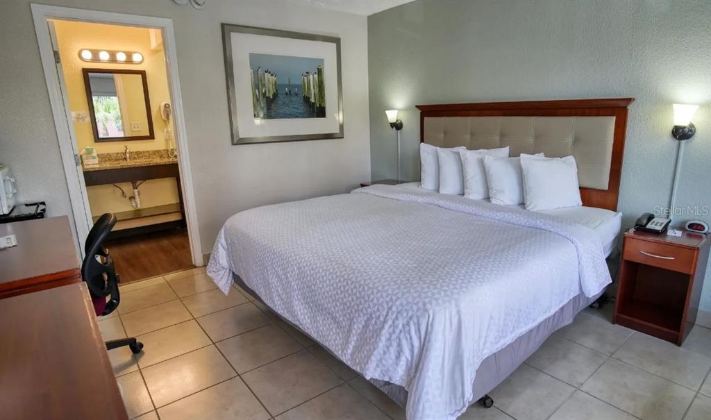 A hotel room features a king bed, tiled floors, a desk, and an attached bathroom — 504 S GULFVIEW BOULEVARD, CLEARWATER, FL