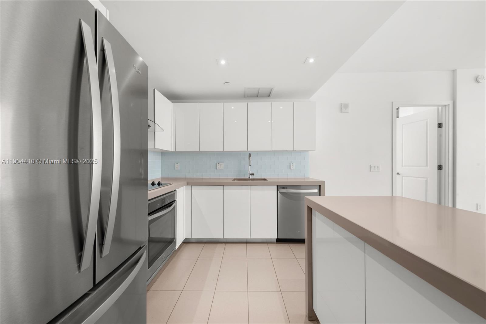 A modern kitchen features white cabinets, stainless steel appliances, and light-colored countertops — 1600 NE 1st Ave # 3016, Miami FL 33132, MIAMI, FL