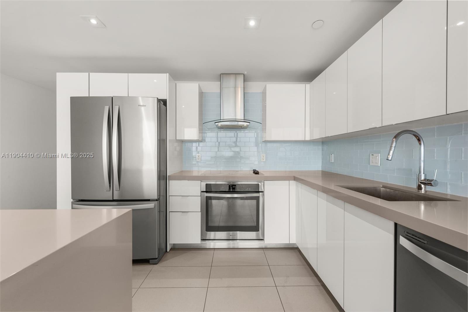 A modern kitchen features white cabinets, stainless steel appliances, and a light blue tiled backsplash — 1600 NE 1st Ave # 3016, Miami FL 33132, MIAMI, FL