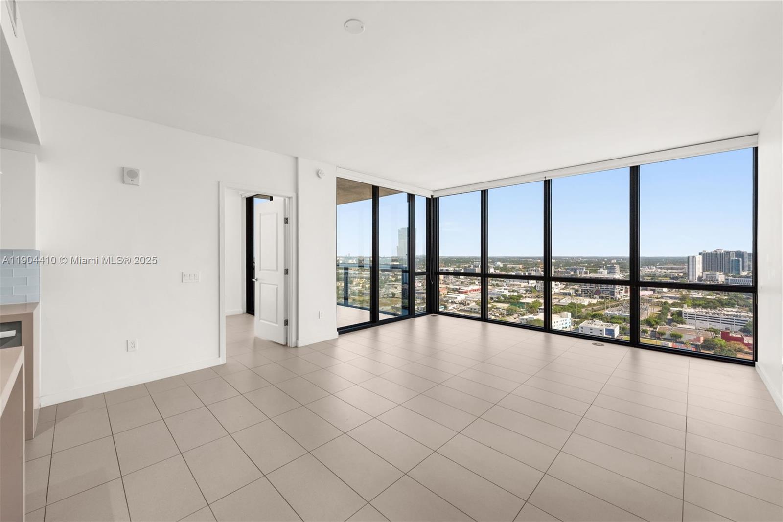 A bright, modern living room features large floor-to-ceiling windows and light-colored tile flooring — 1600 NE 1st Ave # 3016, Miami FL 33132, MIAMI, FL