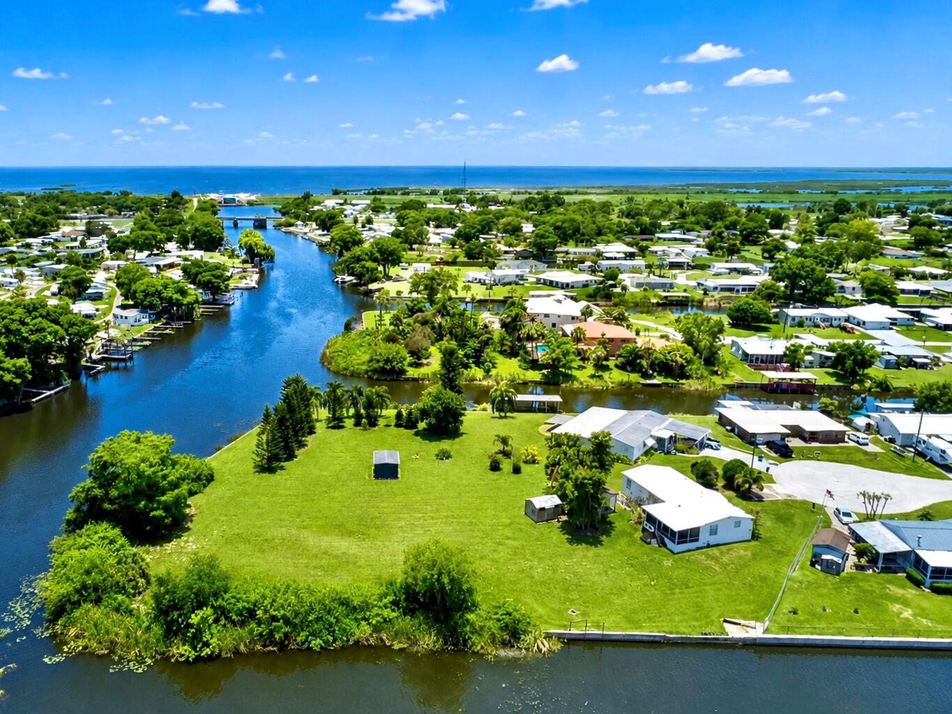 An aerial view shows a grassy waterfront lot with a small house and canal access — 2717 SE 32nd Street, Okeechobee FL 34974, OKEECHOBEE, FL