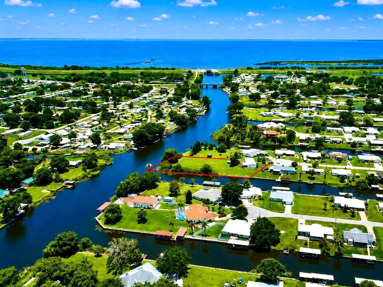 An aerial view shows a vacant waterfront lot outlined in red within a residential community — 2717 SE 32nd Street, Okeechobee FL 34974, OKEECHOBEE, FL