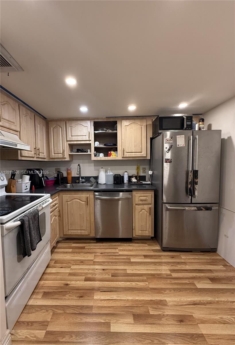 A kitchen features light wood cabinets, stainless steel appliances, and wood-look laminate flooring — 4176 Inverrary Dr # 103, Lauderhill FL 33319, LAUDERHILL, FL