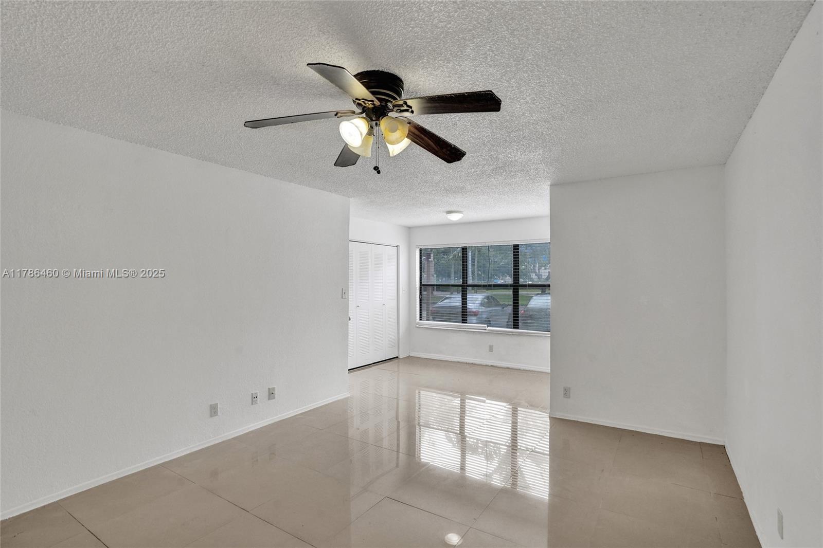 An empty room features white walls, light-colored tile flooring, a ceiling fan, and a window — 2946 S University Dr # 7108, Davie FL 33328, DAVIE, FL