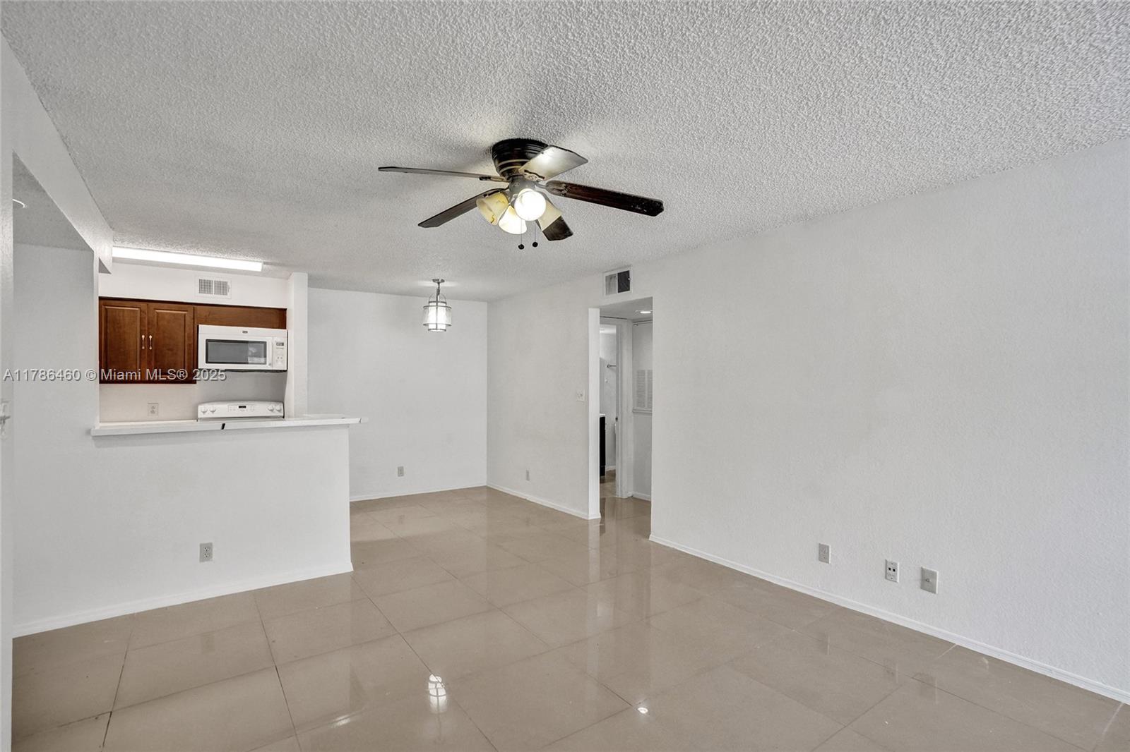 An open-concept living and dining area features a ceiling fan, tiled floors, and a kitchen — 2946 S University Dr # 7108, Davie FL 33328, DAVIE, FL