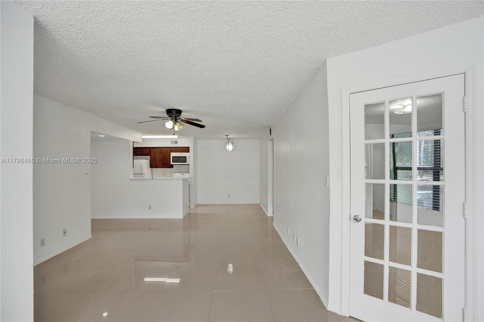 An open-concept living and dining area features white walls, tile flooring, and a ceiling fan — 2946 S University Dr # 7108, Davie FL 33328, DAVIE, FL
