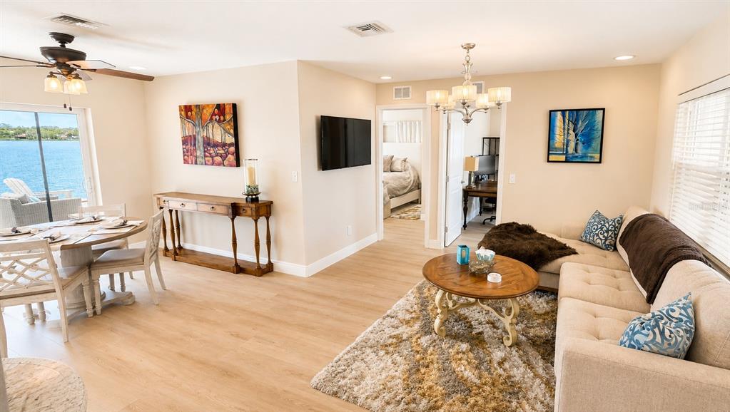 An open-concept living and dining area features light wood flooring, a waterfront view, and furniture — 526 20TH AVENUE, INDIAN ROCKS BEACH, FL