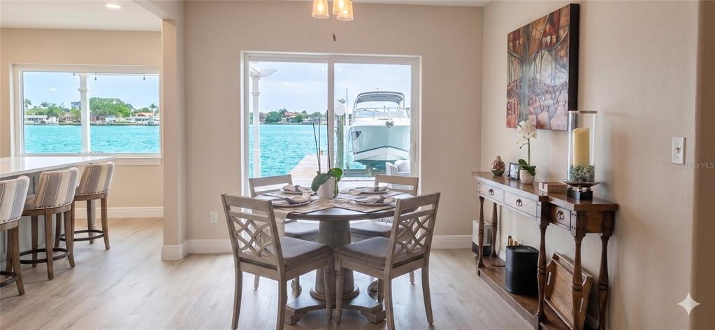 A dining area with a round table, chairs, and a console table overlooking a boat dock — 526 20TH AVENUE, INDIAN ROCKS BEACH, FL