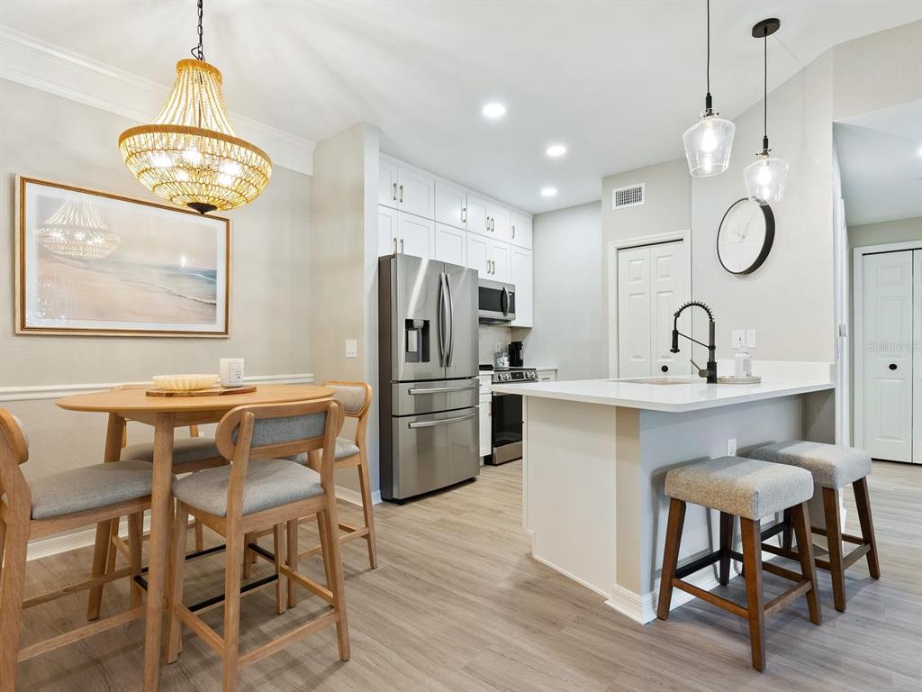A kitchen and dining area with light wood flooring, white cabinetry, and stainless steel appliances — 5168 NORTHRIDGE ROAD UNIT 102, SARASOTA, FL