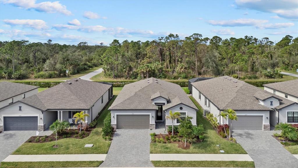 An aerial view shows three modern single-story suburban houses with paved driveways and landscaped lawns — 2081 GARDENIA AVENUE, PORT CHARLOTTE, FL