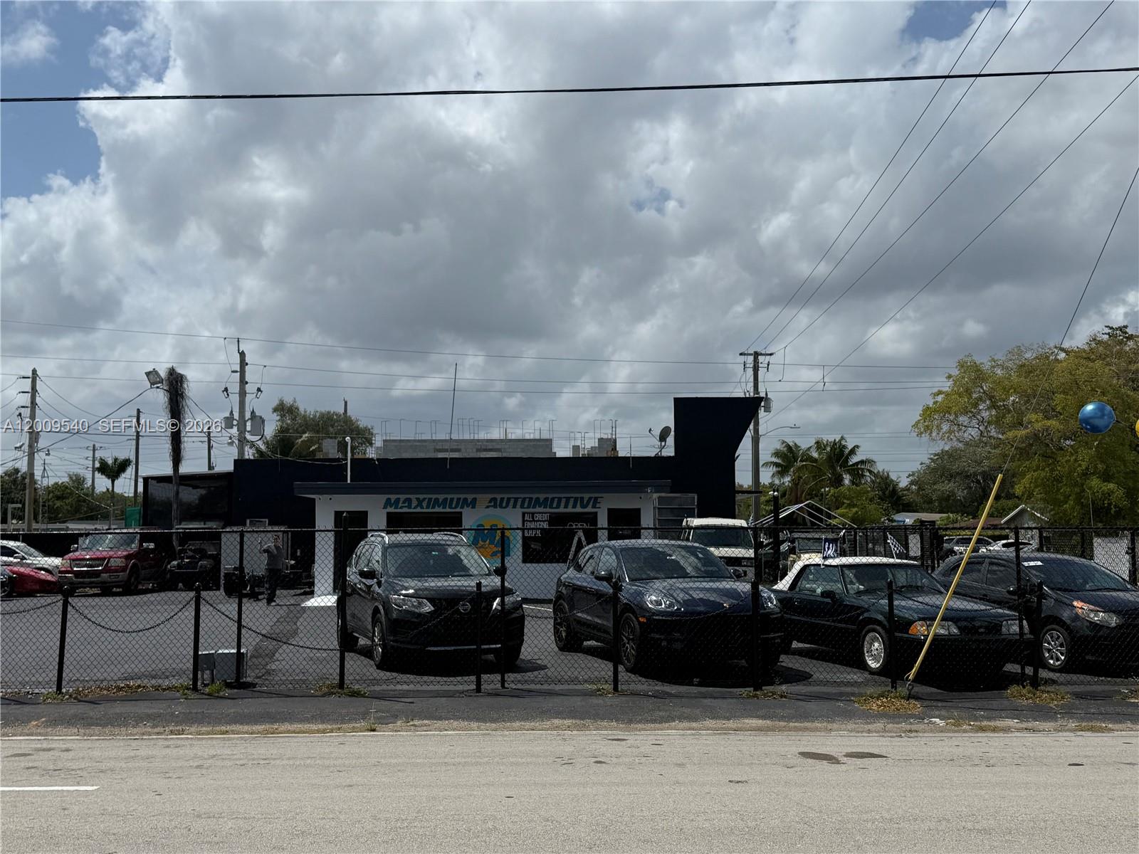 A car dealership lot features several vehicles parked in front of a building named Maximum Automotive — 1822 N Dixie Hwy, Hollywood FL 33020, HOLLYWOOD, FL