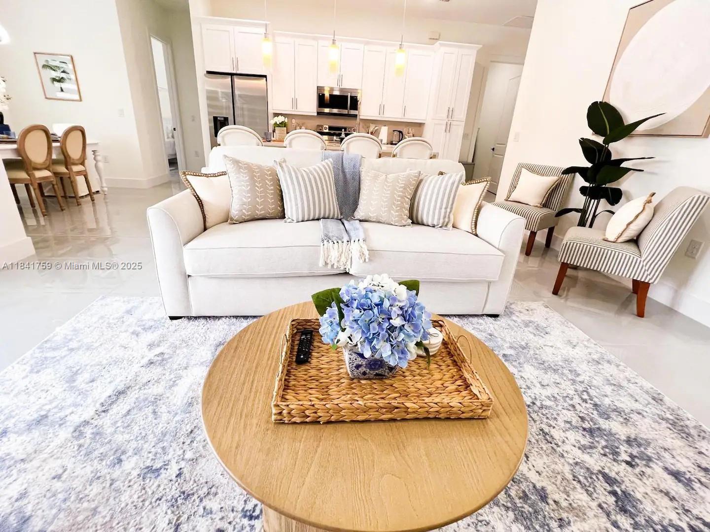 A living room features a white sofa, a round wooden coffee table, and an open kitchen — 404 NW 1st ST, Cape Coral FL 33993, CAPE CORAL, FL
