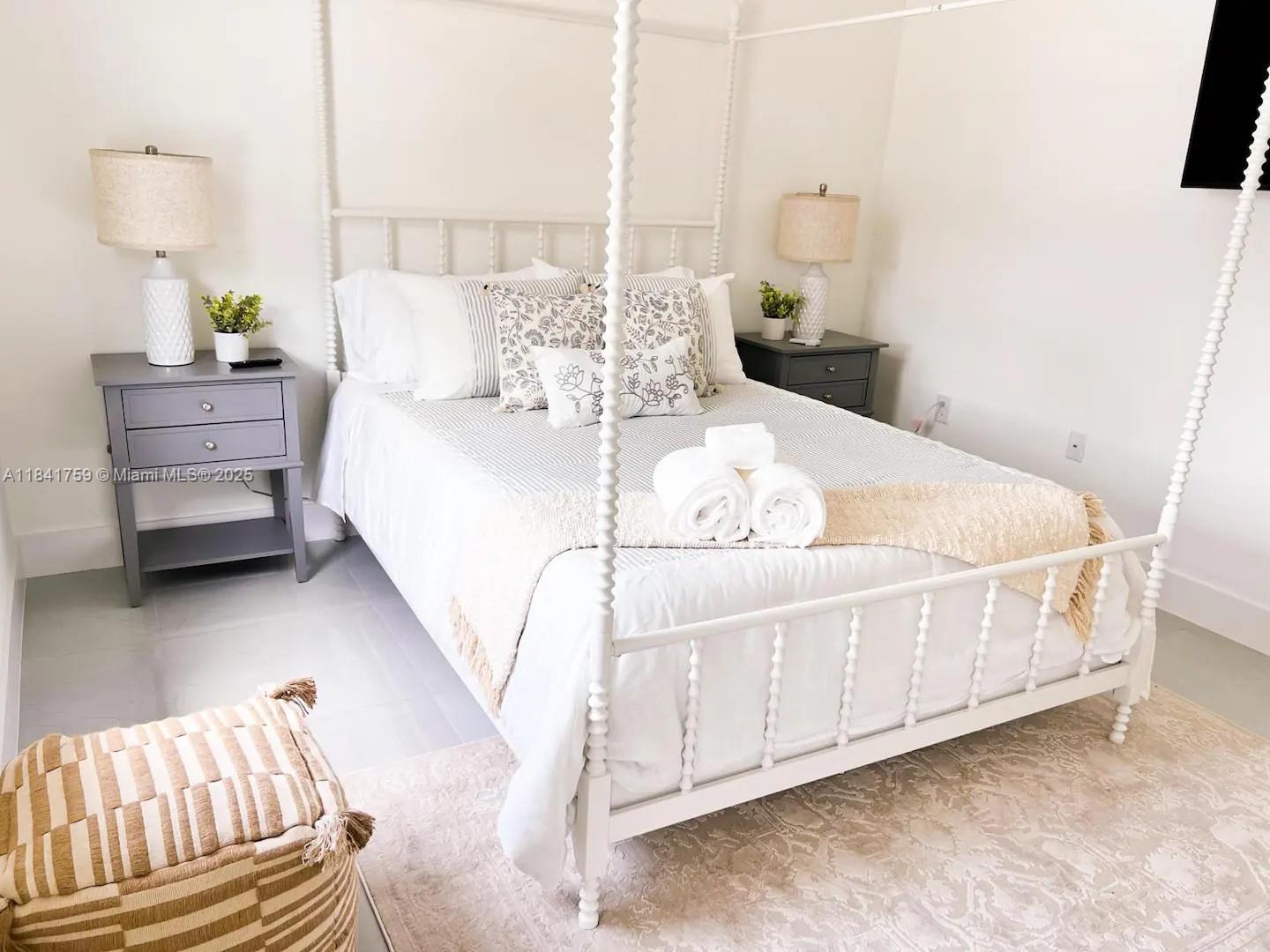 A bedroom features a white four-poster bed, two gray nightstands, and a patterned area rug — 404 NW 1st ST, Cape Coral FL 33993, CAPE CORAL, FL