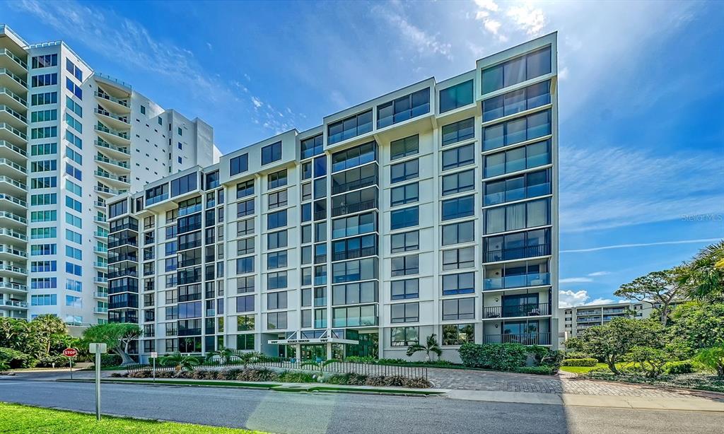 A multi-story residential building with white exterior walls and glass balconies under a blue sky — 707 S GULFSTREAM AVENUE UNIT 705, SARASOTA, FL