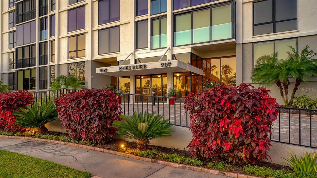 The exterior entrance of a multi-story apartment building features a covered walkway and landscaping — 707 S GULFSTREAM AVENUE UNIT 705, SARASOTA, FL