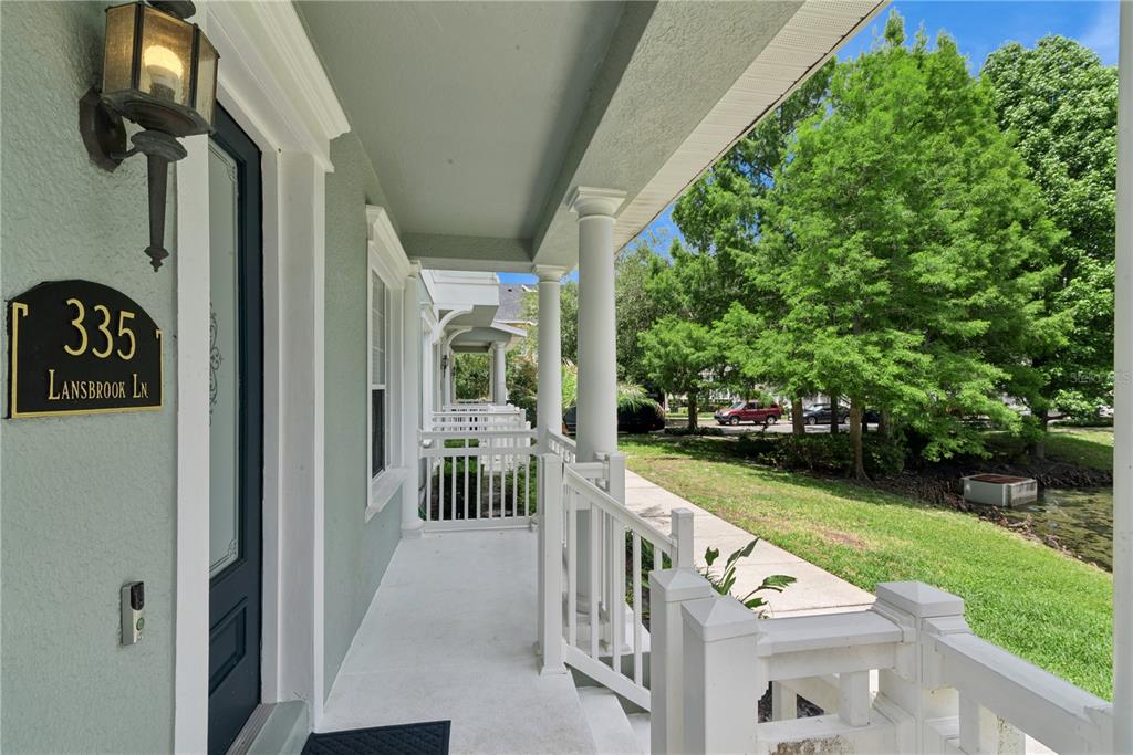 A covered front porch features white railings, columns, and a view of a grassy area — 335 LANSBROOK LANE, WINTER SPRINGS, FL